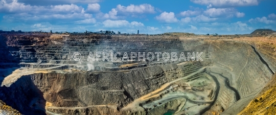 Deep Open Pit Diamond Mine with Terraced Rock Walls and Dust Plu