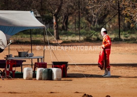 Clown in Costume Standing in Dusty Circus Encampment  makeshift 